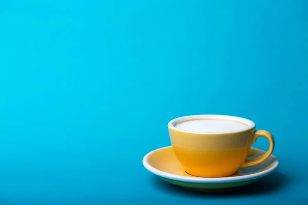 Gelbe Tasse auf blauem Hintergrund — Stockfoto