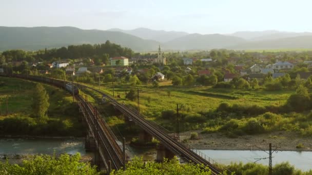 Поїзд Йде Мостом Через Гірське Село Освітлене Променями Сонця — стокове відео