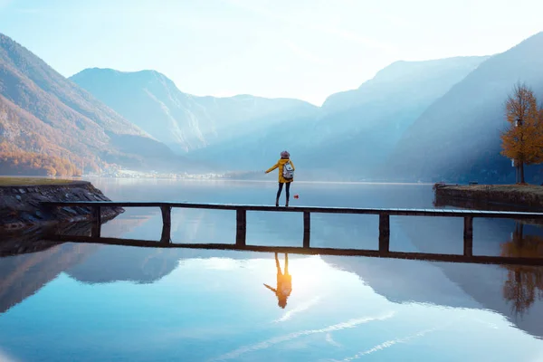 Ragazza turistica in un cappello e con uno zaino seduto su un br di legno — Foto Stock