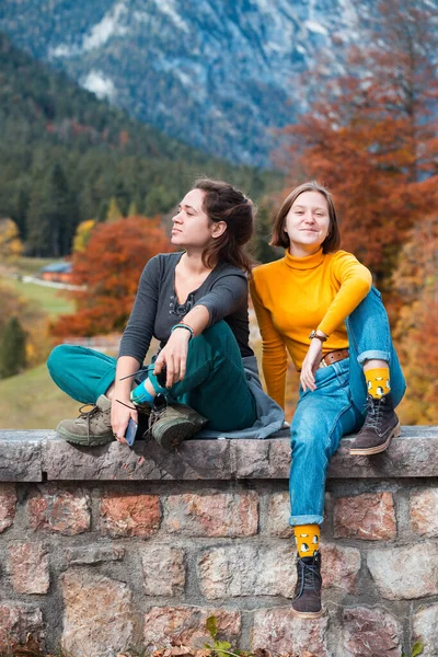 2人の幸せな女の子の観光客が山の風景を背景にリラックス座っている 活動的なライフスタイル — ストック写真