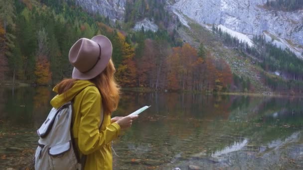 バックパックを持った少女探検家が美しい山の湖の観光地図を見て — ストック動画