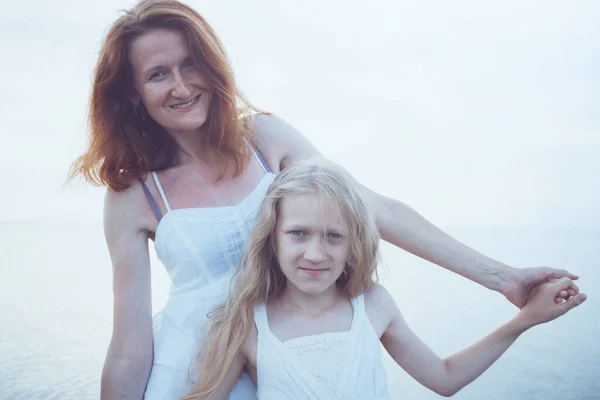 海で幸せな家族の週末 日没時に海を歩く白いドレスのお母さんと娘 ウクライナのアゾフ海の風景 — ストック写真