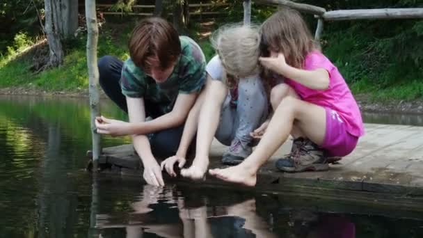 Çocuklar Göl Kıyısında Ayakları Suyun Içinde Oturuyorlar — Stok video