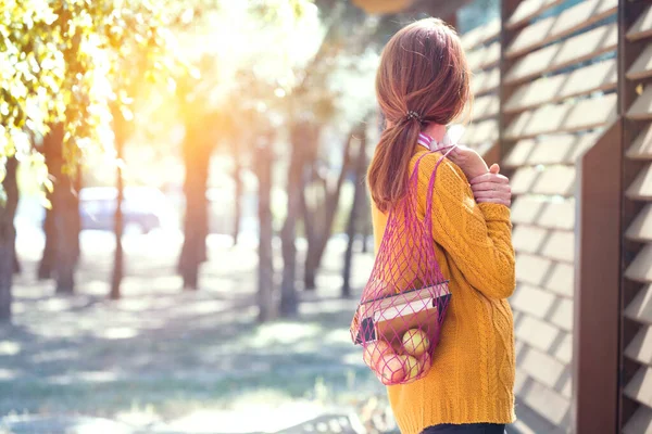 本とりんごが入ったメッシュバッグを持って公園の女の子 秋のムーー — ストック写真