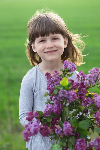 ライラックの花束を持つ牧草地の美しい女の子 — ストック写真