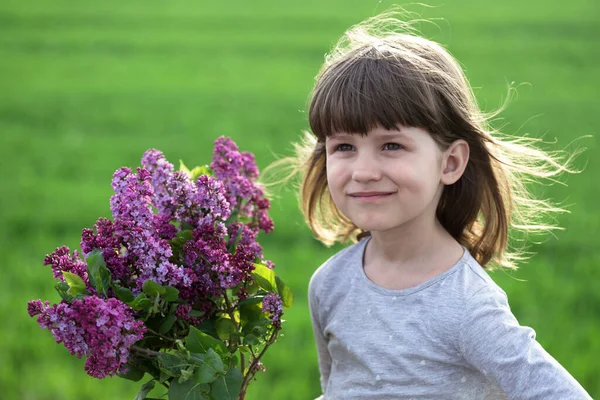 ライラックの花束を持つ牧草地の美しい女の子 — ストック写真
