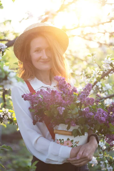 帽子の美しい女の子とライラックの花束を庭で一時停止 — ストック写真