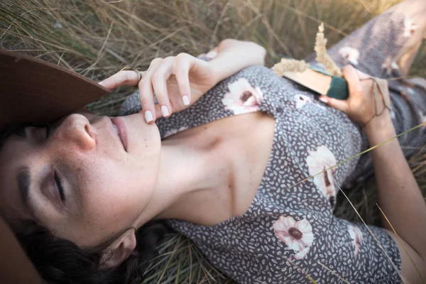 stock image happy smiling girl lies in dry grass with book. retro style