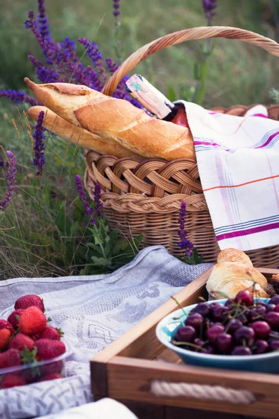 Summer - picnic in the meadow. Cheese brie, baguette, strawberry, cherry, wine, croissants and baske