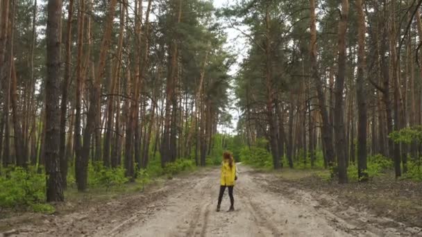 Улыбающаяся Туристка Желтой Куртке Рюкзаком Идущая Сосновой Лесной Дороге — стоковое видео