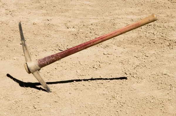 Pick Ax plunged into dirt ground — Stock Photo, Image