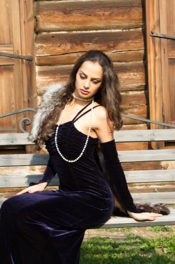 Eski bir malikanenin arka planında gece elbisesi giymiş genç bir kızın portresi