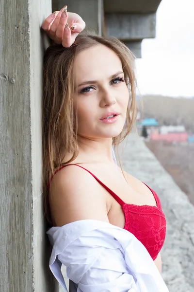 Lány vörös fehérnemű, és fehér ing, a háttérben a betonszerkezetek. — Stock Fotó