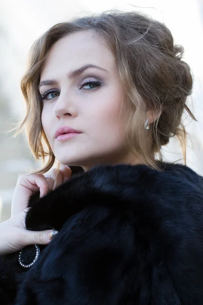 Hermosa joven con un abrigo de piel negro — Foto de Stock
