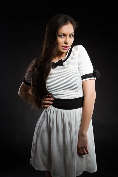 Mooi jong meisje in een witte jurk op een zwarte achtergrond. Studio portret. — Stockfoto