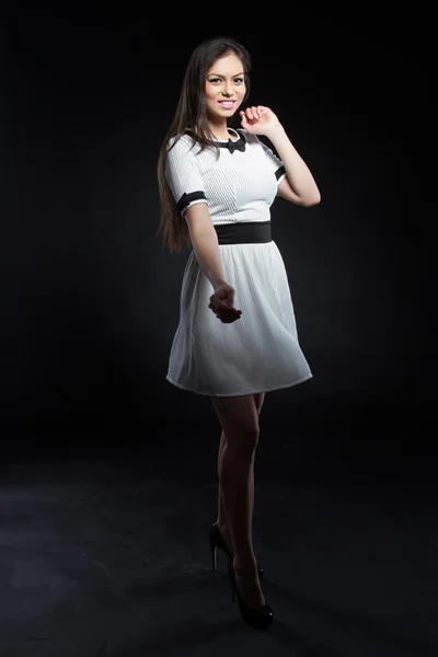 美丽的年轻女孩，在黑色背景上的白色礼服。工作室画像. — 图库照片
