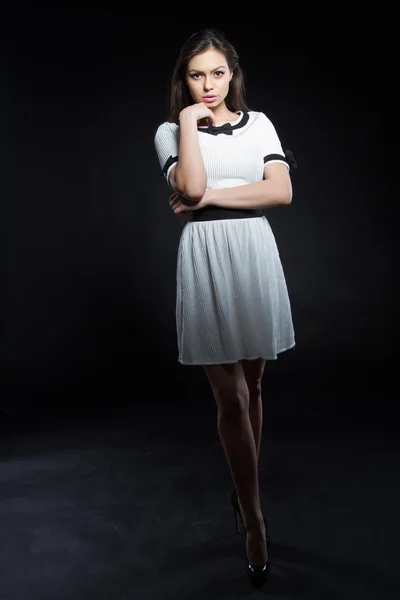 Beautiful young girl in a white dress on a black background. Studio portrait. — Stock Photo, Image