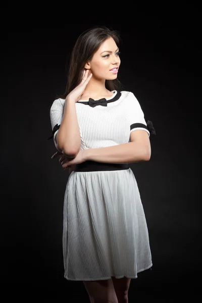美丽的年轻女孩，在黑色背景上的白色礼服。工作室画像. — 图库照片