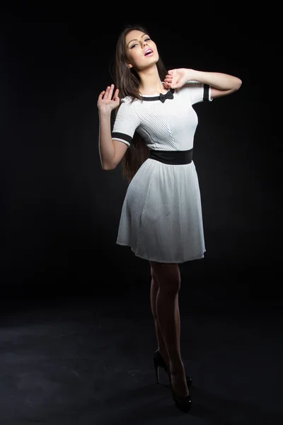 Mooi jong meisje in een witte jurk op een zwarte achtergrond. Studio portret. — Stockfoto