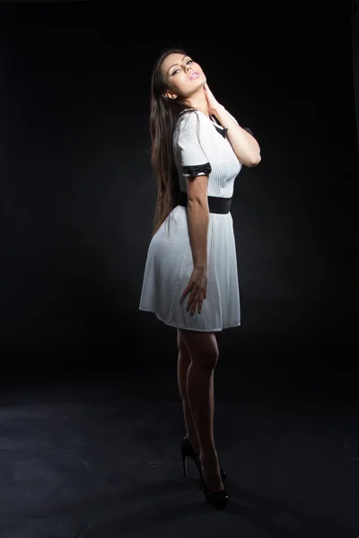 Beautiful young girl in a white dress on a black background. Studio portrait. — Stock Photo, Image