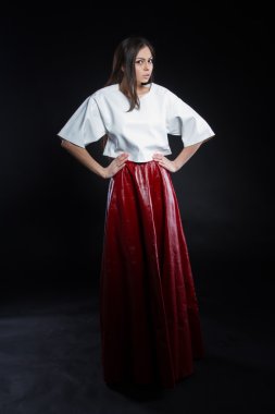 Güzel genç kız beyaz bir bluz ve siyah bir zemin üzerine uzun etek kırmızı. Stüdyo portre.