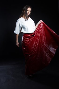 Güzel genç kız beyaz bir bluz ve siyah bir zemin üzerine uzun etek kırmızı. Stüdyo portre.