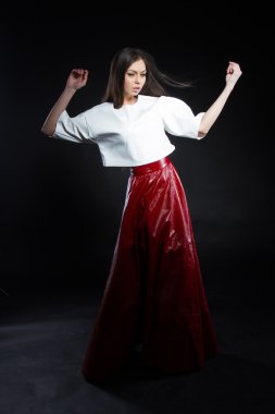 Güzel genç kız beyaz bir bluz ve siyah bir zemin üzerine uzun etek kırmızı.