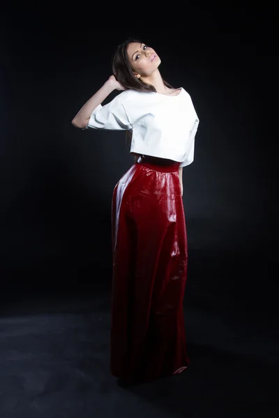 Menina bonita em uma blusa branca e uma saia longa vermelha em um fundo preto . — Fotografia de Stock