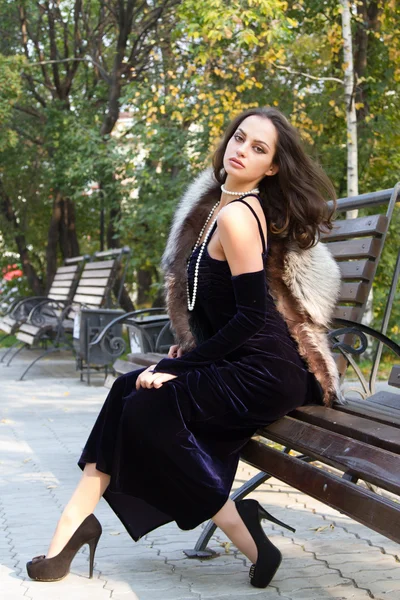 Girl sits on a bench in autumn park — Stock Photo, Image