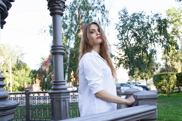 Menina em uma camisa branca de pé em um gazebo de metal — Fotografia de Stock