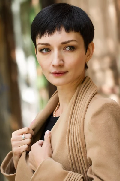 Girl with short hair on the background of an old wooden house — Stockfoto