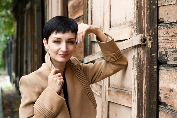 Girl with short hair on the background of an old wooden house — Φωτογραφία Αρχείου