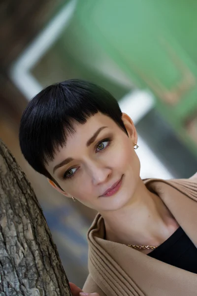 Girl with short hair on the background of an old wooden house — Stockfoto