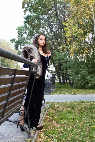 Girl in evening dress walks on autumn park — Stockfoto
