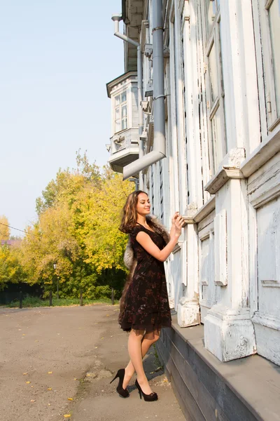 Portret van een jong meisje op een achtergrond van een oud houten huis — Stockfoto