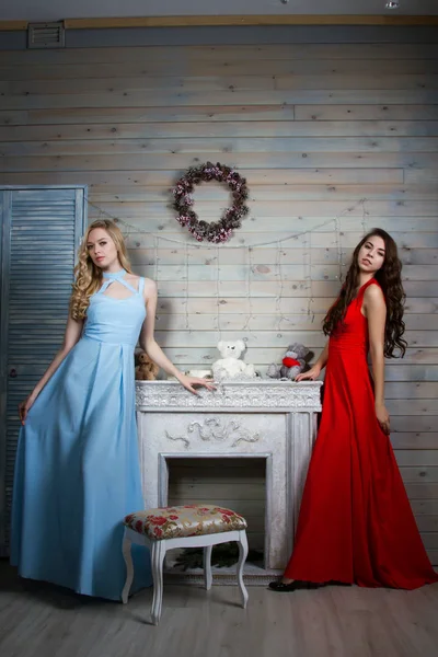 Zwei junge Mädchen in langen Kleidern in einem Raum mit Kamin — Stockfoto