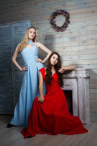 两个年轻的年轻女孩，穿长礼服在一个房间里的壁炉 — 图库照片