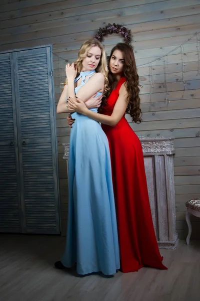 Dos chicas jóvenes en vestidos largos en una habitación con chimenea —  Fotos de Stock
