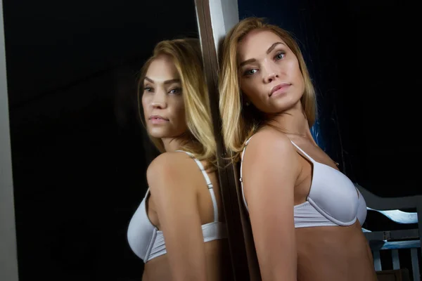Blondin i vita underkläder kostar en stor spegel — Stockfoto