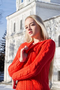 Kilise bir arka plan üzerinde kırmızı bir kazak sarışın