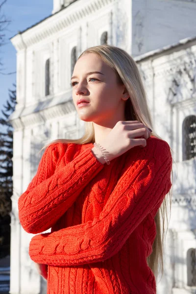 Blonde in a red sweater on a background of church