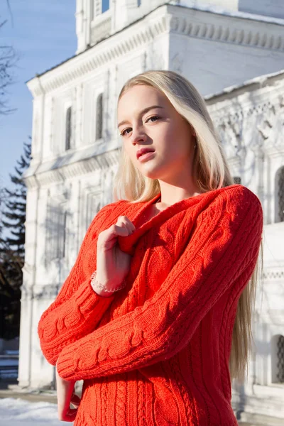 Blondin i en röd tröja på en bakgrund av kyrkan — Stockfoto