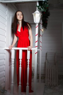 Kız evin verandada bir kırmızı Abiye ayakta.