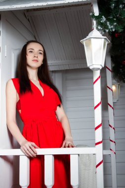 Kız evin verandada bir kırmızı Abiye ayakta.