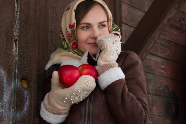 Girl with a red apple on a background of an old wooden house — Stock Photo, Image