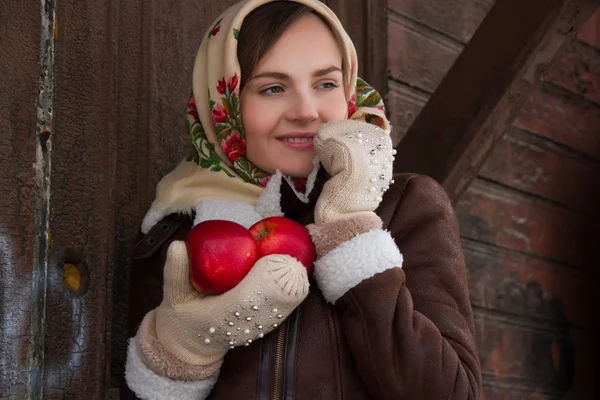 Girl with a red apple on a background of an old wooden house — Stock Photo, Image