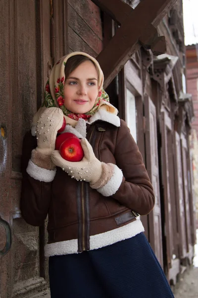 Mädchen mit einem roten Apfel auf dem Hintergrund eines alten Holzhauses — Stockfoto