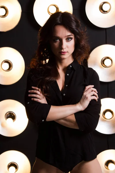 Young girl in shirt and shorts on a background of powerful lamps — Stock Photo, Image