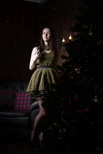 Schlanke junge Frau im kurzen Kleid steht neben einem Weihnachtsbaum — Stockfoto