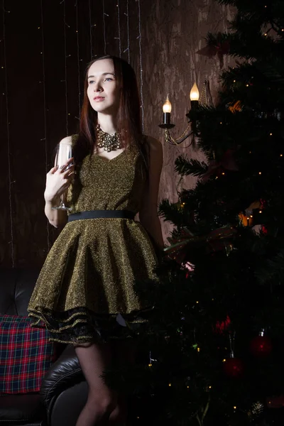 Schlanke junge Frau im kurzen Kleid steht neben einem Weihnachtsbaum — Stockfoto